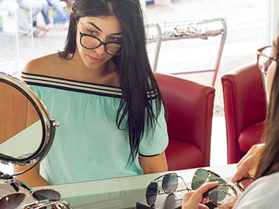 Grande variedade de modelos de óculos Mulher provando óculos
