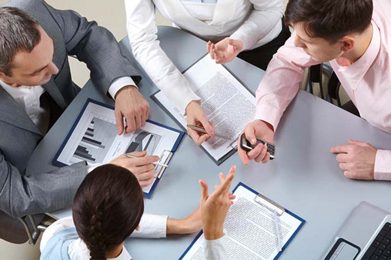 Consultoria contábil Equipe reunida ao redor de uma mesa analisando relatórios e documentos contábeis