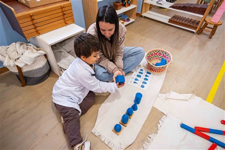 Professora acompanhando criança em atividade Montessori