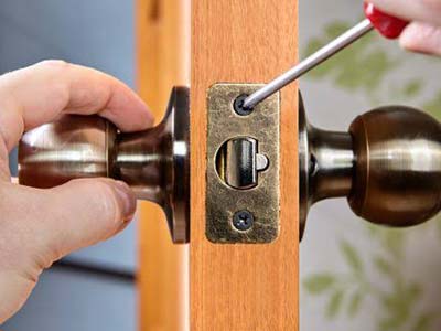 Serviço de chaveiro em Araçatuba Profissional fazendo a manutenção de uma fechadura com maçaneta em porta de madeira