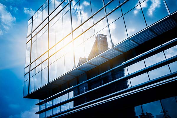 Fachada de vidro de um edifício comercial refletindo o céu