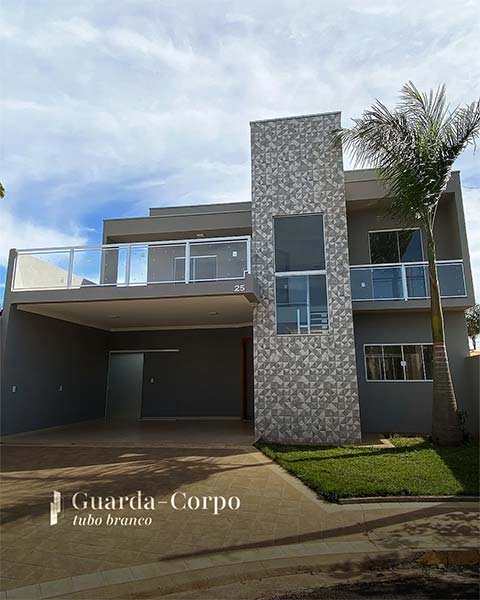 Guarda-corpo de vidro com tubo branco na sacada de uma casa de dois pavimentos
