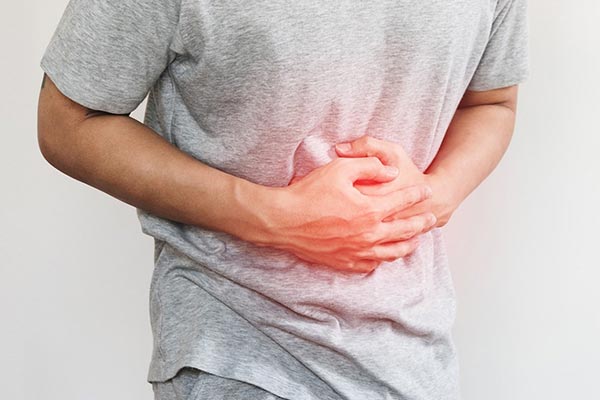 Homem com a mão sobre o abdômen sentindo desconforto intestinal