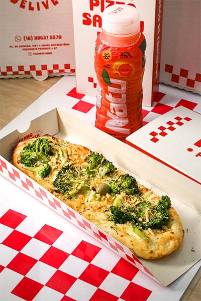 Pizza salgada com suco como acompanhamento Pizza salgada com brócolis na embalagem individual da Fiamme acompanhada de suco