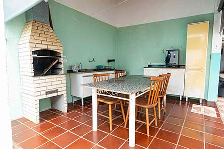 Área de lazer com churrasqueira Área de lazer coberta com churrasqueira de tijolos, mesa com cadeiras e pia