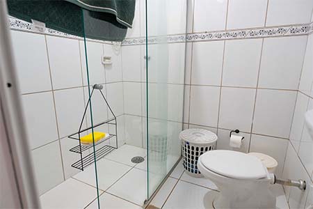 Banheiro da suíte Banheiro da suíte com box de vidro, vaso sanitário e revestimento branco