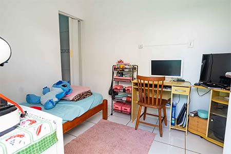 Quarto individual com escrivaninha Quarto individual com cama de solteiro, tapete rosa, escrivaninha e estante
