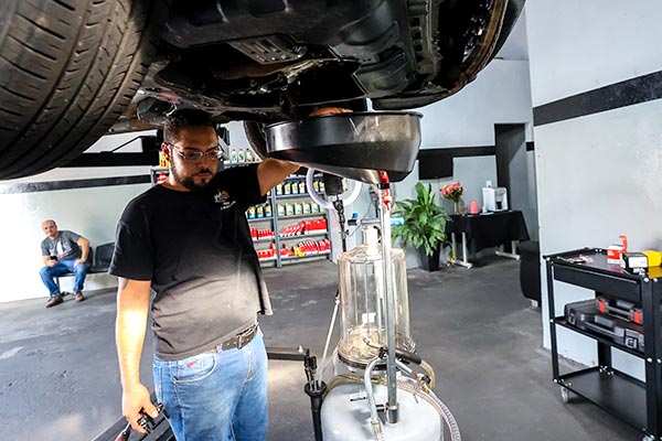 Troca de óleo rápida Profissional da MS Lubrificantes abastecendo o motor com óleo novo usando funil