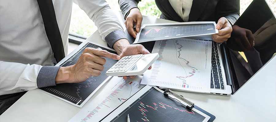 Profissionais analisando relatórios financeiros com calculadora Profissionais analisando relatórios financeiros com calculadora