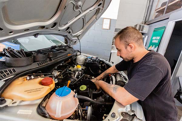 Mecânico realizando revisão automotiva em carro na oficina
