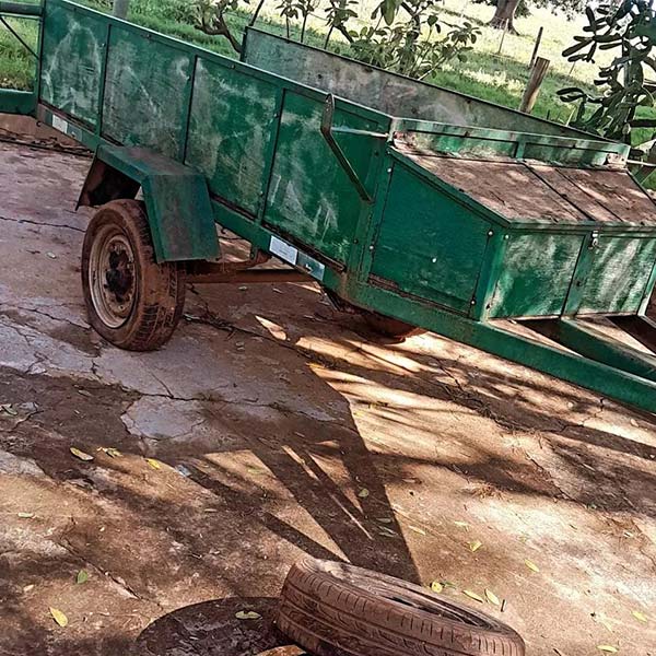 Troca de pneu de carretinha – Borracharia Móvel do Fabrício Carretinha verde estacionada em terreno de terra com pneu sobressalente no chão para troca