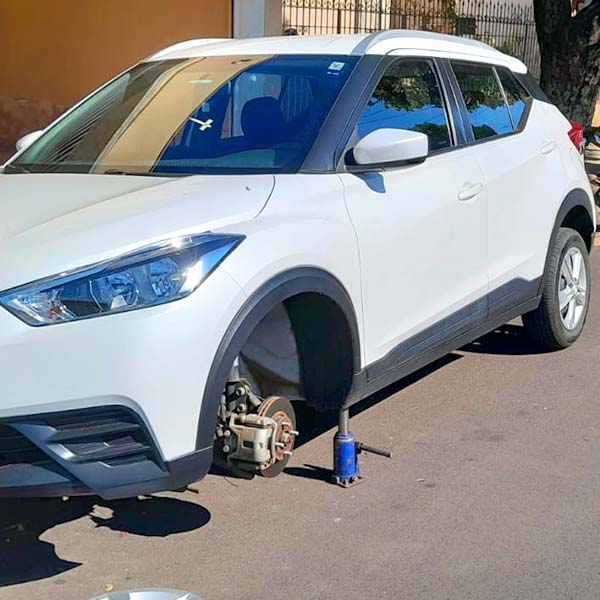 Troca de pneu de carro no local – Borracharia Móvel do Fabrício SUV branco suspenso por macaco hidráulico durante troca de pneu na rua, atendimento da Borracharia Móvel do Fabrício em Araçatuba
